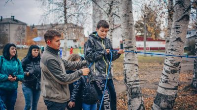 Kids enjoying an outdoor rope activity among birch trees during fall.