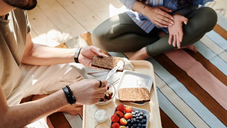High angle view of a couple having a healthy breakfast with bread and fruits indoors.